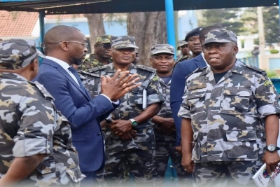 Ministro da Defesa Nacional, Cristóvão Chume, em terno, ao lado de militares da Marinha de Guerra de Moçambique.